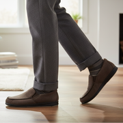 Men's brown slip-on slippers worn with gray pants cuff and black sole