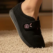Black women’s slip-on slippers with pink floral emblem on front strap