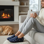 Women’s navy slippers on feet with white flower print and black sole, indoor wear