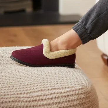 Burgundy slippers with beige sherpa collar and black sole, worn with rolled jeans