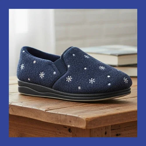 Women’s navy slip-on slippers with white daisy print and black sole on wooden platform